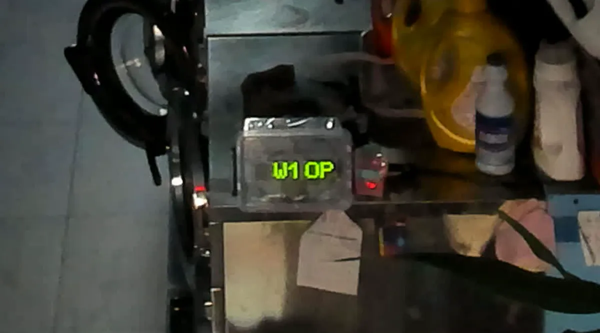 The store camera, zoomed, reading the W1 board through its clear case: “W1 OP”